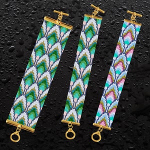 Puede incluir: Tres pulseras de cuentas con patrones geométricos en tonos de verde, rosa y azul. Las pulseras tienen cierres dorados y están dispuestas sobre un fondo negro.