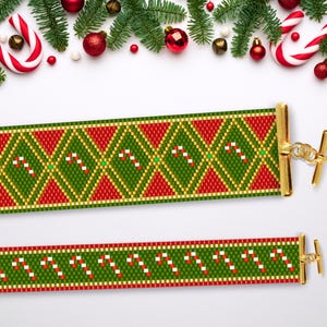 Puede incluir: Dos pulseras de cuentas con temática navideña. La pulsera superior presenta un patrón de diamantes verde, rojo y dorado con bastones de caramelo. La pulsera inferior presenta un patrón de rayas verde, rojo y dorado con bastones de caramelo.