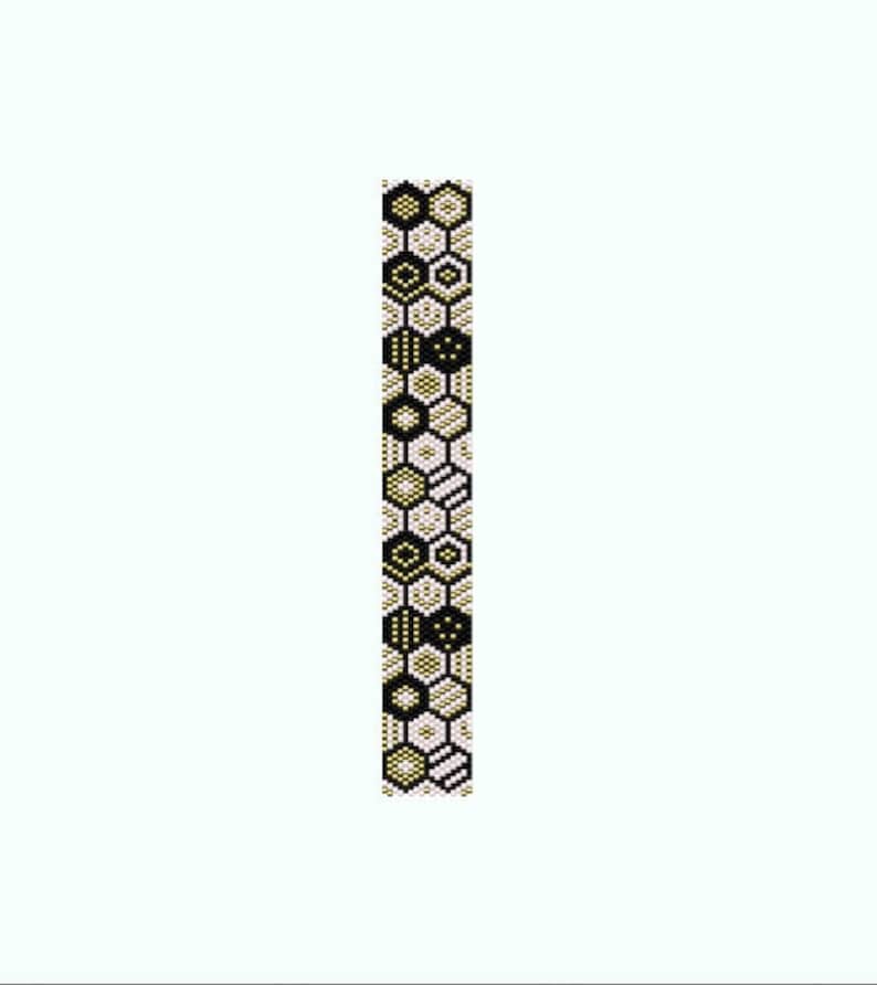 Puede incluir: Un brazalete de cuentas negras, blancas y doradas con un patr&oacute;n geom&eacute;trico de hex&aacute;gonos.