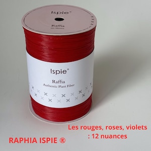 Peut inclure: Une bobine de raphia rouge, une fibre végétale authentique, avec une étiquette blanche. L'étiquette indique "Ispie Raffia Authentic Plant Fiber". La bobine contient 120 mètres de raphia. Le texte "RAPHIA ISPIE" est également visible.