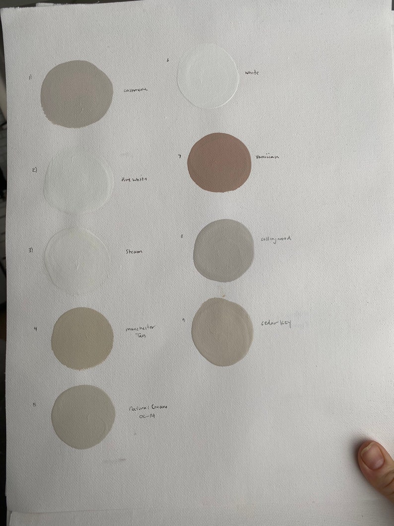 May include: A white sheet of paper with ten paint swatches in various shades of white, beige, and brown. The swatches are labeled with names like "cashmere", "white", "venetian", "straw", "calling wood", "manchester tan", "cedar key", and "natural cream 02-14".
