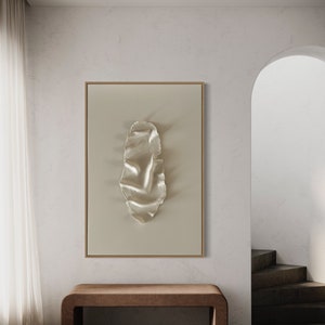 May include: A framed abstract art print with a white, textured, organic shape on a beige background. The print is hanging on a white wall above a brown wooden bench.