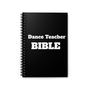 May include: A black spiral-bound notebook with the text "Dance Teacher BIBLE" in white, bold lettering. The notebook is closed and appears unused.