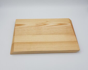 May include: A natural wood cutting board with a light brown color and a smooth surface.