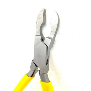 Könnte beinhalten: Eine Zange mit gelben Griffen und einem silbernen Metallkopf. Die Zange hat ein einzigartiges Design mit einer abgerundeten Öffnung oben.