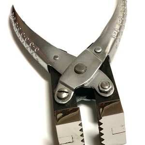 以下が含まれることがあります： 黒いハンドルと、ギザギザの縁のある2つの正方形の顎を持つ銀色の金属製のペンチ。顎は圧着用に設計されています。