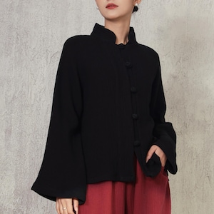 May include: A black jacket with a mandarin collar and three buttons, paired with red pants. The jacket has wide sleeves and is worn by a person.