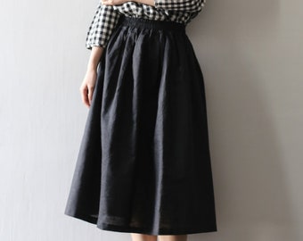 May include: A black midi skirt with an elastic waistband. The skirt is made of a lightweight fabric and has a flowy silhouette.