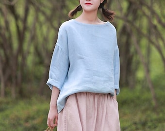 May include: A light blue linen top with a relaxed fit and three-quarter sleeves. The top is paired with a pink linen skirt.