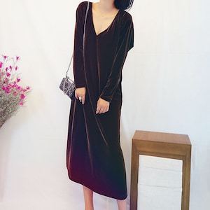 May include: A long-sleeved brown velvet dress with a V-neckline. The dress is midi-length and has a relaxed fit.