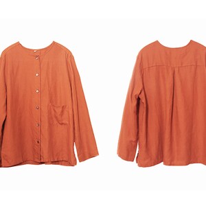 May include: A long-sleeved, button-up shirt in a burnt orange colour. The shirt has a simple design with a single pocket on the left side.