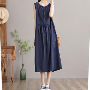 May include: A navy blue sleeveless midi dress with a button-up front and a gathered waist. The dress is made of a lightweight fabric and has a relaxed fit.