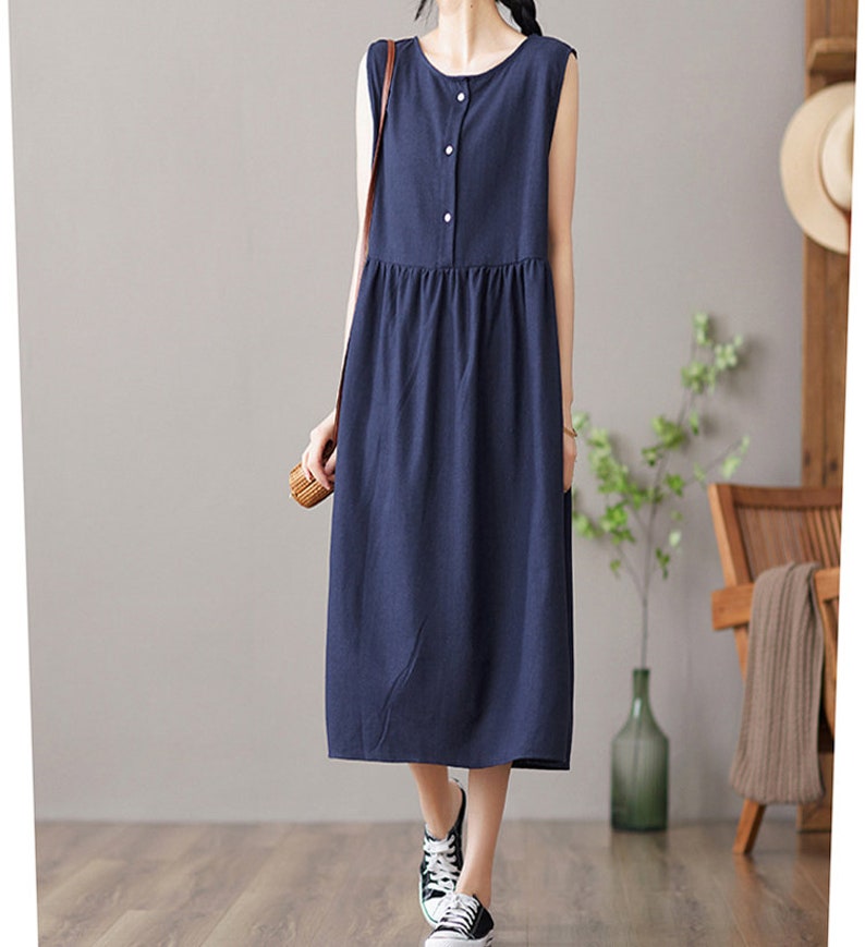 May include: A navy blue sleeveless midi dress with a button-up front and a slightly gathered skirt.