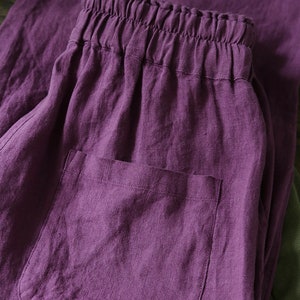 May include: Purple linen pants with a drawstring waistband and a patch pocket. The pants are made of a soft, comfortable fabric and have a relaxed fit.