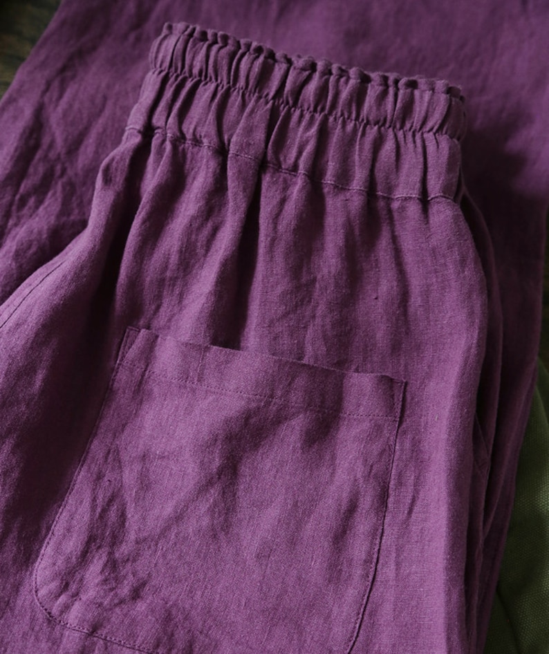 May include: Purple linen pants with a drawstring waistband and a patch pocket. The pants are made of a soft, comfortable fabric and have a relaxed fit.