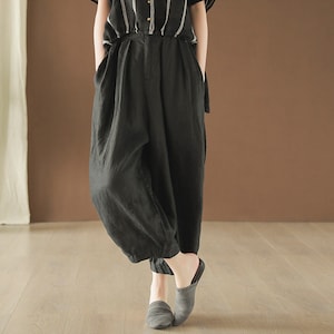 May include: Black linen pants with a wide leg and a loose fit. The pants have a high waist and are made of a soft, comfortable fabric.