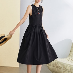May include: A black sleeveless midi dress with a gathered waist and two pockets. The dress is made of a lightweight fabric and has a relaxed fit.