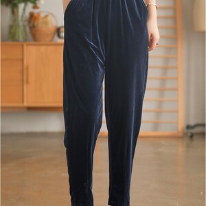 May include: Dark blue velvet pants with a wide waistband and a relaxed fit.