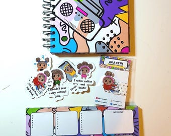 May include: A spiral-bound notebook with a colorful abstract pattern featuring a boombox, a weekly planner pad with white rectangular sections for days of the week, and several die-cut stickers and a magnetic bookmark depicting a character reading books.