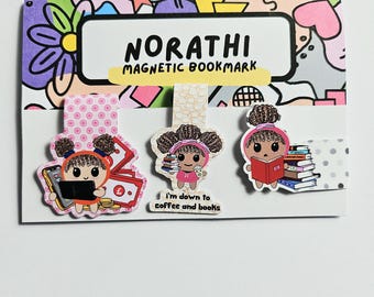 May include: Three magnetic bookmarks on a display card labeled NORATHI MAGNETIC BOOKMARK. The left bookmark shows a character with a phone and money. The center bookmark features a character with coffee and books, text reads I'm down to coffee and books. The right bookmark shows a character reading a stack of books.