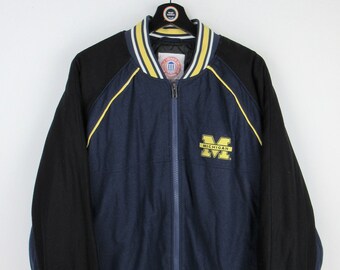 May include: A navy blue and black bomber jacket with yellow and white striped trim. The jacket has a zip closure and a large "Michigan" logo on the front.