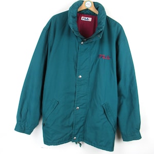 Peut inclure: Une veste bleu sarcelle avec une doublure rouge et un logo Fila sur le devant. La veste a une fermeture éclair et un cordon de serrage au bas.