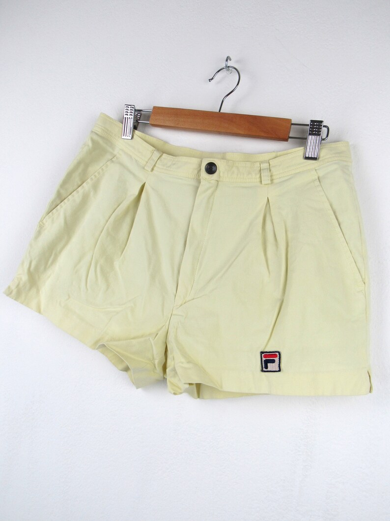 May include: Pale yellow athletic shorts with a small red, white, and blue "F" logo on the right leg.