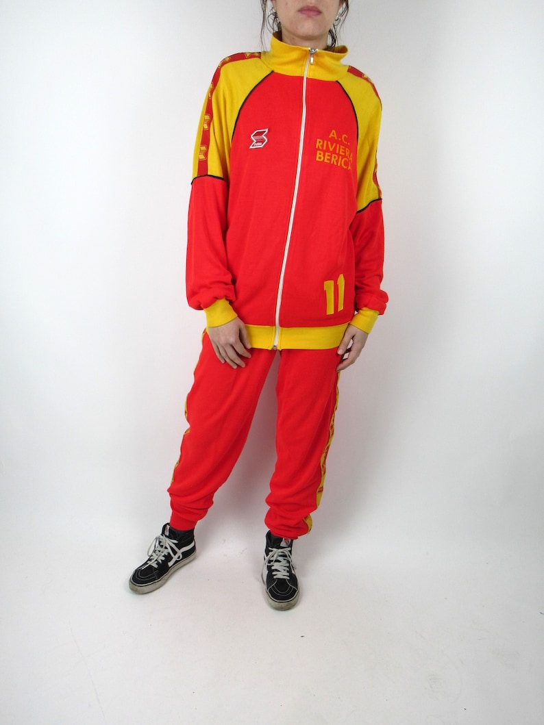 Puede incluir: Ch&aacute;ndal rojo y amarillo con rayas negras y el texto "A.C. RIVIERA BERICA" y el n&uacute;mero "11" en la chaqueta.