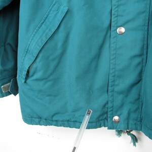May include: Teal blue jacket with a zipper and button closure. The jacket has a pocket on the left side and a drawstring at the bottom.