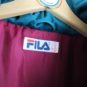 May include: A teal blue Fila jacket with a maroon lining. The jacket has a size tag that reads "I 54 D 54 F Y USA 44 J 34L".