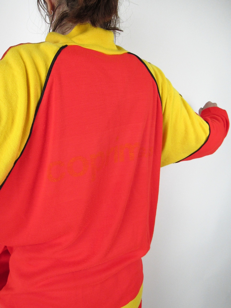 Puede incluir: Sudadera roja y amarilla con ribetes negros y la palabra "COFFIN" impresa en la espalda.