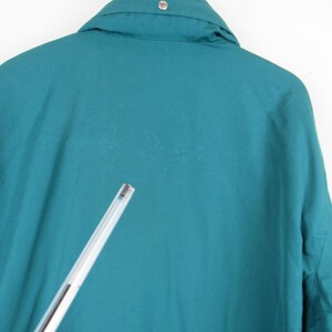 May include: Teal blue jacket with a button on the collar.