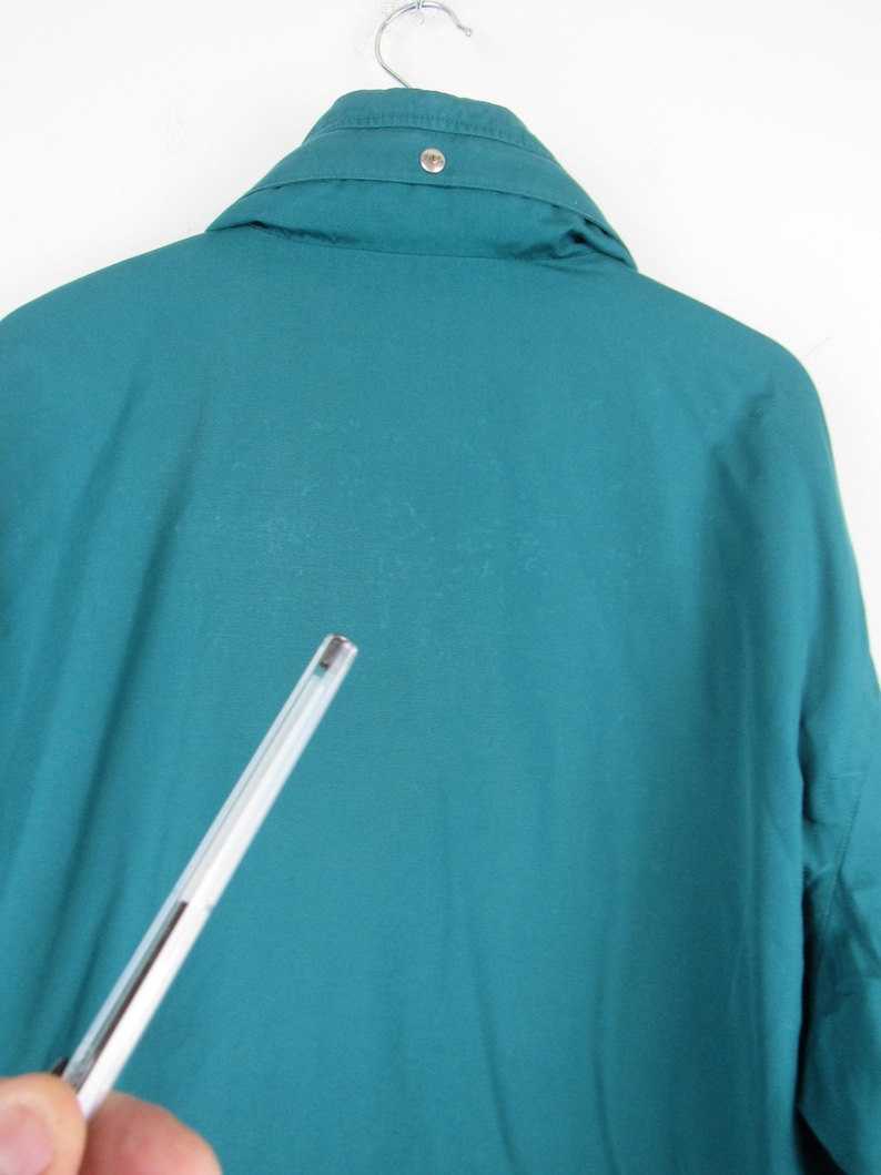 May include: Teal blue jacket with a button on the collar.