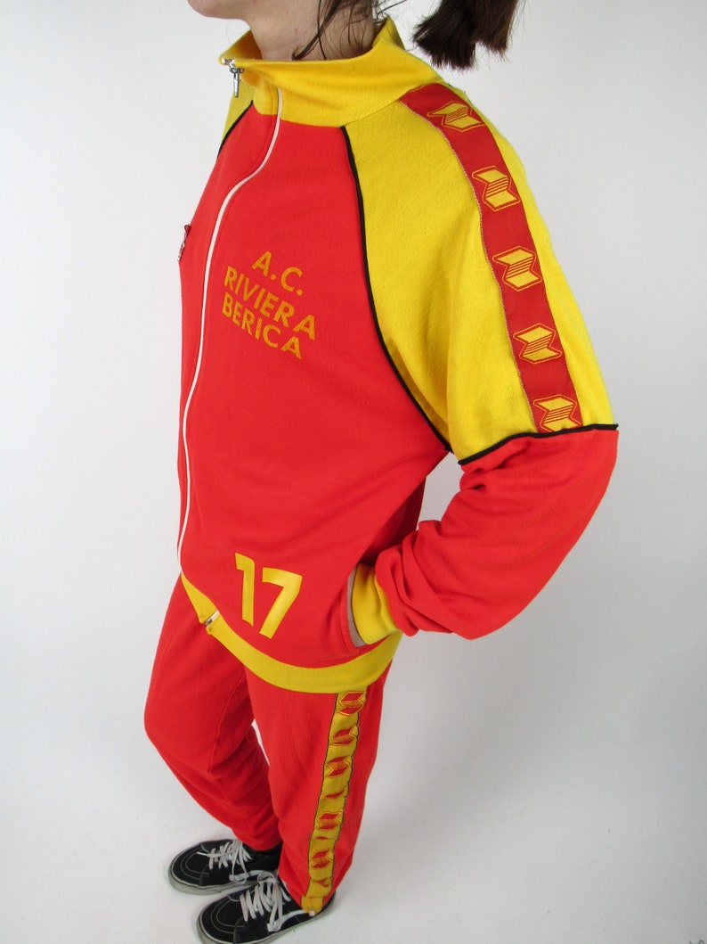 Puede incluir: Ch&aacute;ndal rojo y amarillo con el texto "A.C. RIVIERA BERICA" y el n&uacute;mero "17" en la parte delantera.