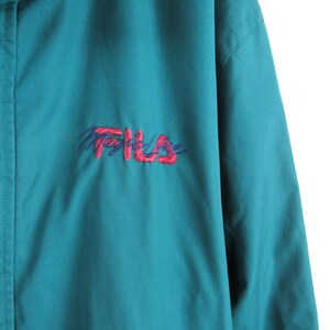 May include: Teal blue jacket with a red and purple embroidered Fila logo.