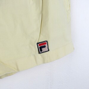 May include: A pair of yellow shorts with a small black and red "F" logo on the right side.