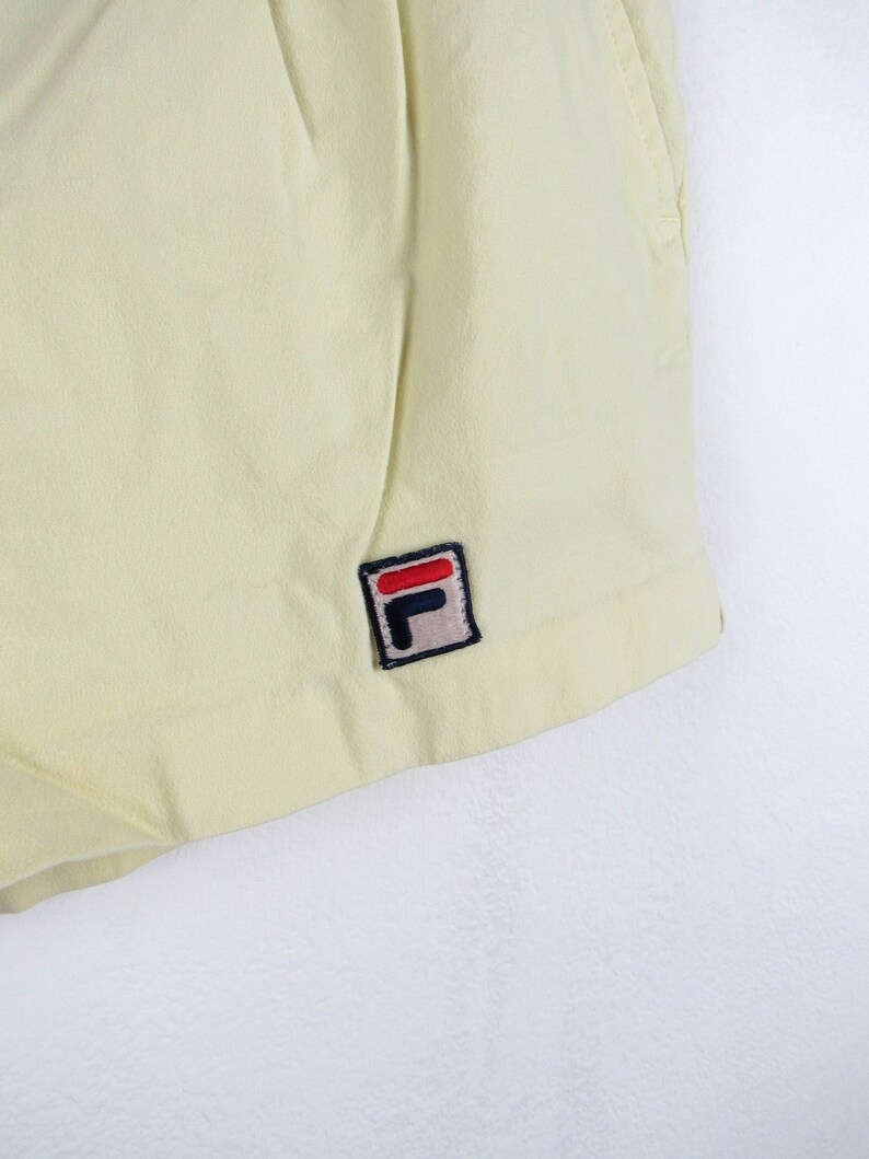 May include: A pair of yellow shorts with a small black and red "F" logo on the right side.