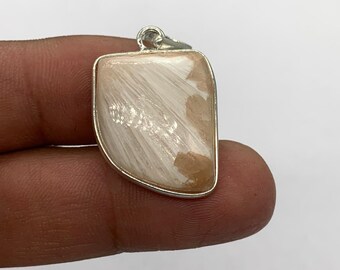 Può includere: Un ciondolo rettangolare con una cornice color argento. Il ciondolo presenta una pietra color crema con un motivo fibroso e piumato e macchie marrone chiaro. Ha un piccolo anello nella parte superiore per una catena.