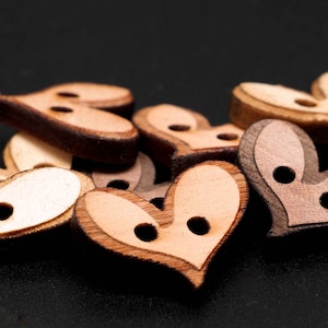 Könnte beinhalten: Nahaufnahme einer Reihe von herzförmigen Holzknöpfen mit jeweils zwei Löchern. Die Knöpfe sind in verschiedenen Brauntönen und Beige.