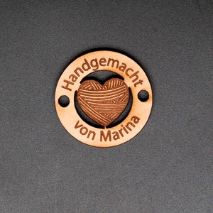 May include: A round wooden tag with the text "Handgemacht von Marina" and a heart-shaped design in the center.
