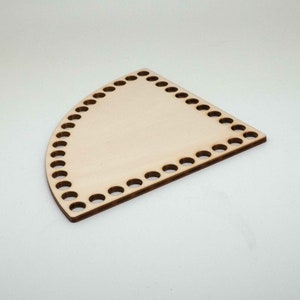 Könnte beinhalten: Ein halbrunder Webrahmen aus Holz mit Löchern am Rand zum Weben.