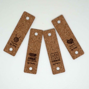 Könnte beinhalten: Vier Kork-Etiketten mit verschiedenen Designs und Texten. Die Etiketten sind rechteckig mit abgerundeten Ecken und zwei Löchern oben. Der Text auf den Etiketten lautet "Handmade by Denny", "Handmade made with love by Andrea", "Handmade by Bianca" und "Handmade made with love by Karin".