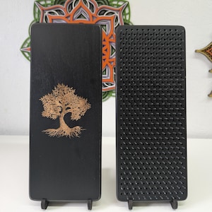Puede incluir: Dos tablas sadhu de madera negra. Una tabla presenta un diseño detallado de árbol en color marrón claro. La otra tabla está cubierta de clavos metálicos negros espaciados uniformemente. Ambas tablas son rectangulares y se mantienen de pie.