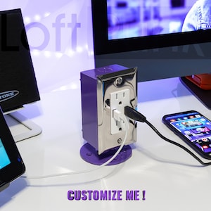 May include: A purple and silver outlet cover with two USB ports and a standard electrical outlet. The outlet cover is mounted on a white surface and is connected to a white cord. The text "CUSTOMIZE ME!" is visible in the lower right corner of the image.