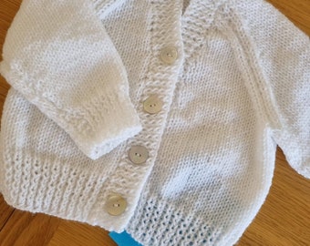 Age 3-6 months. White v neck cardigan with hint of mint sparkle. Mother of pearl buttons. Handknitted super soft.