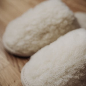May include: A pair of white fluffy slippers made of sheepskin.
