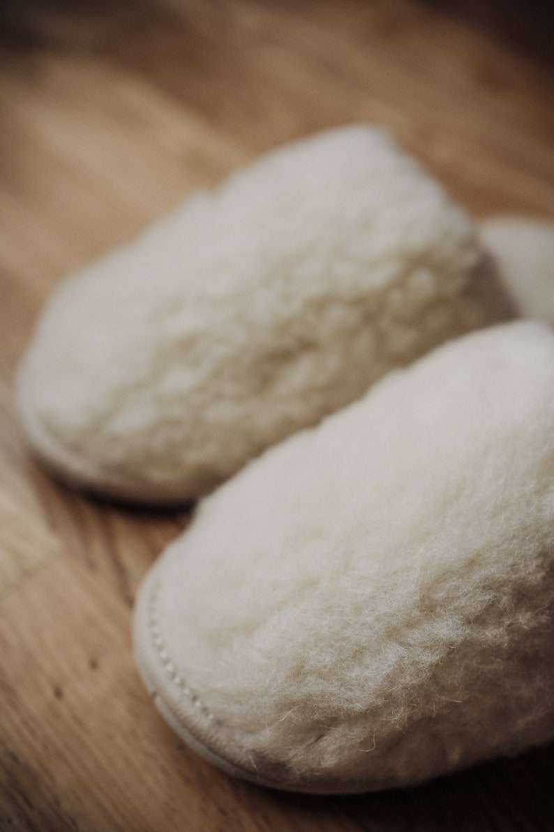 May include: A pair of white fluffy slippers made of sheepskin.