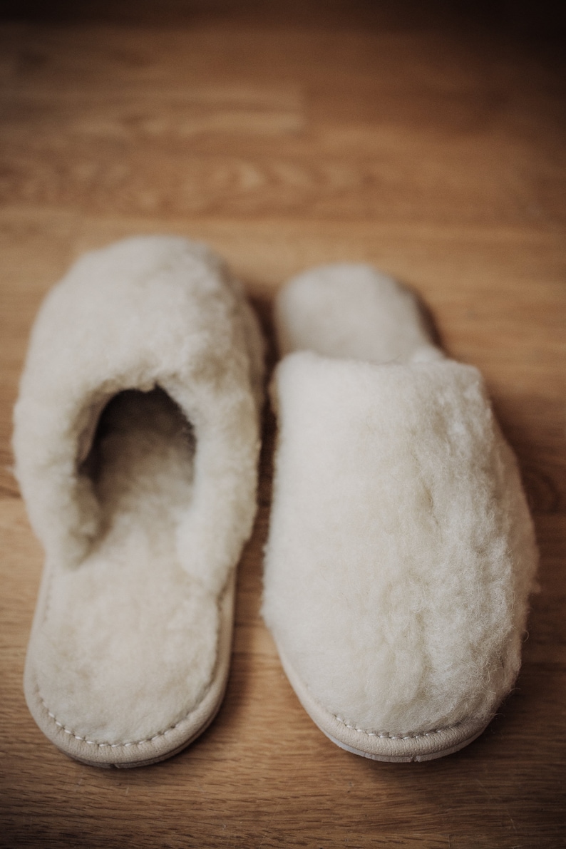 May include: A pair of white fluffy slippers with a closed toe and a soft, fuzzy texture.