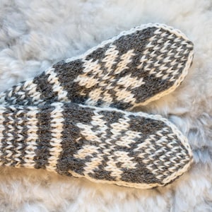 May include: A pair of gray and white knitted mittens with a snowflake pattern.
