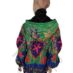May include: A long-sleeved hooded jacket featuring a vibrant, pleated fabric with a colorful marine-themed print. The design includes starfish, seashells, and coral motifs in shades of green, purple, blue, red, and gold, with adjustable drawstrings.